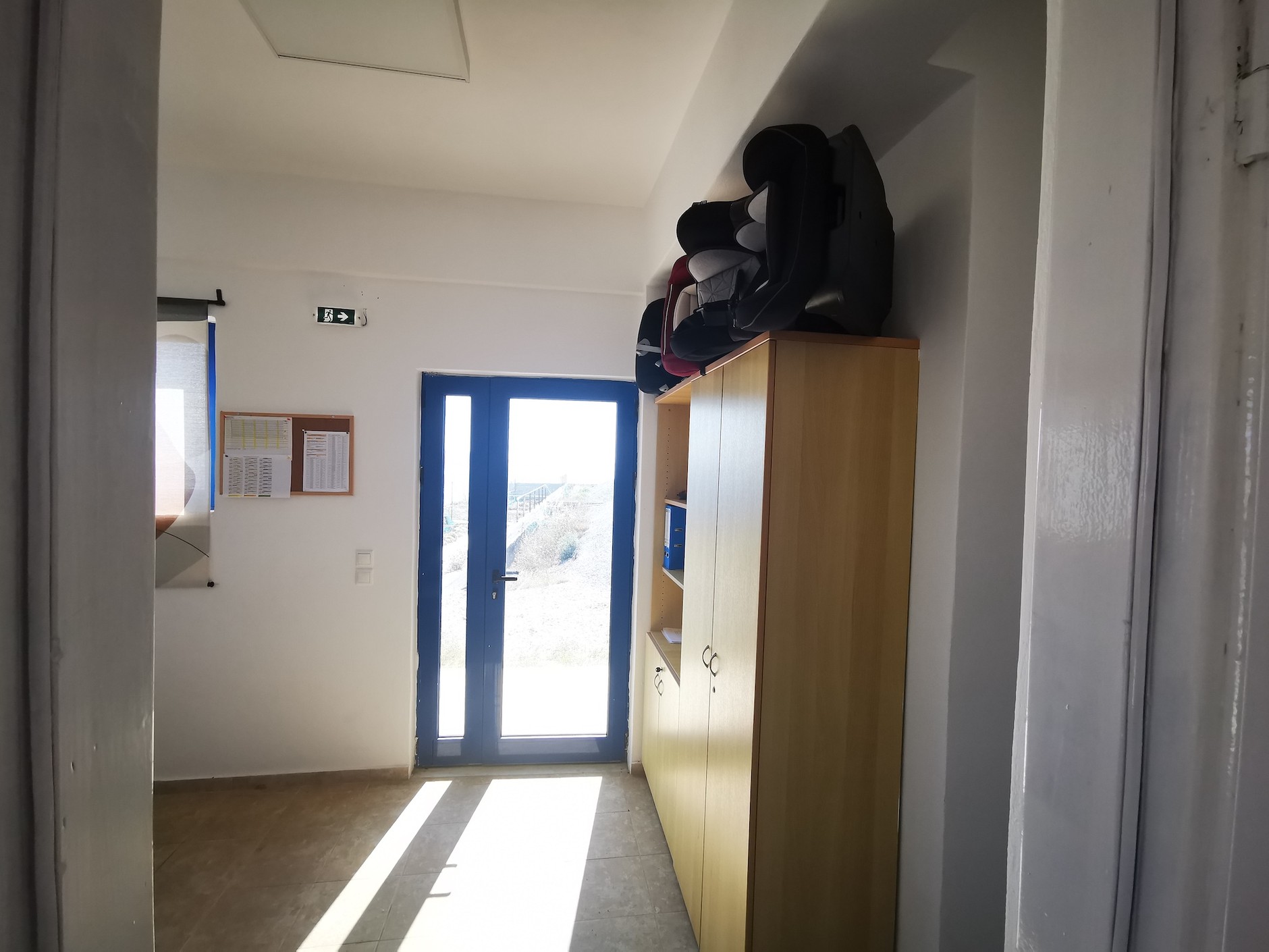 Astypalea: na szafie w skromnym biurze "zajezdni" Astybusów leżą trzy foteliki dla dzieci. Kierowcy biorą je w razie potrzeby