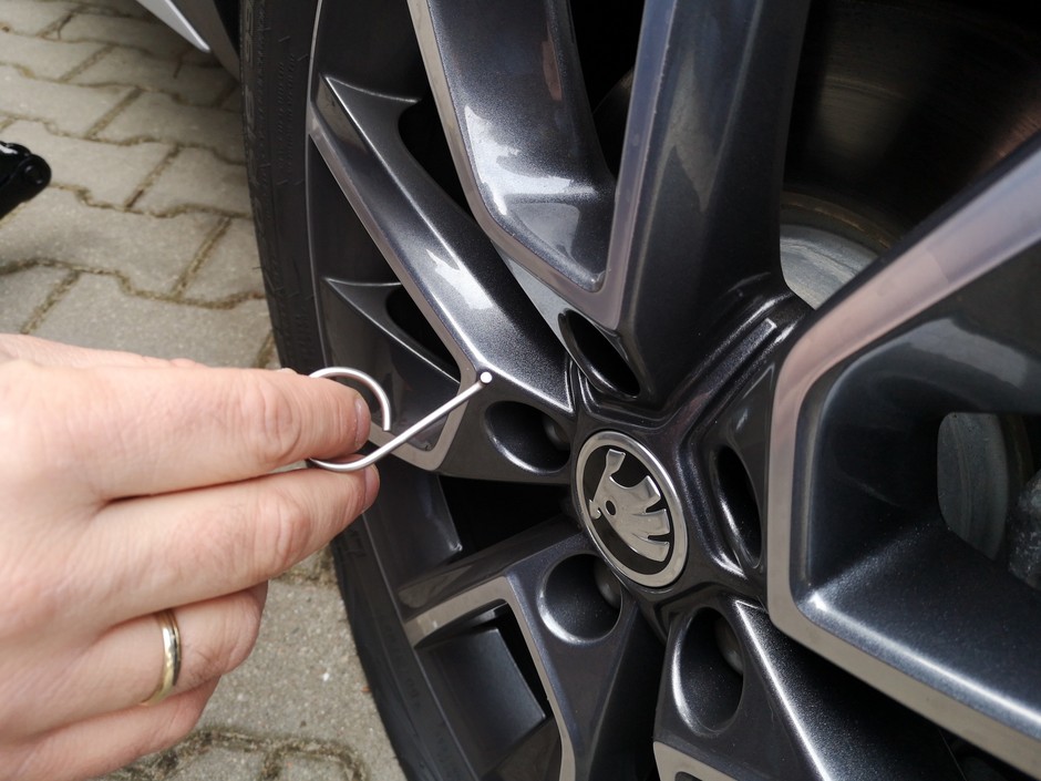 Wymiana koła krok po kroku: niespodzianka – na śrubach są plastikowe nakładki i nie pasuje na nie żaden klucz! Należy je wyciągnąć (specjalnym kluczem, ale można i zwykłym wkrętakiem).